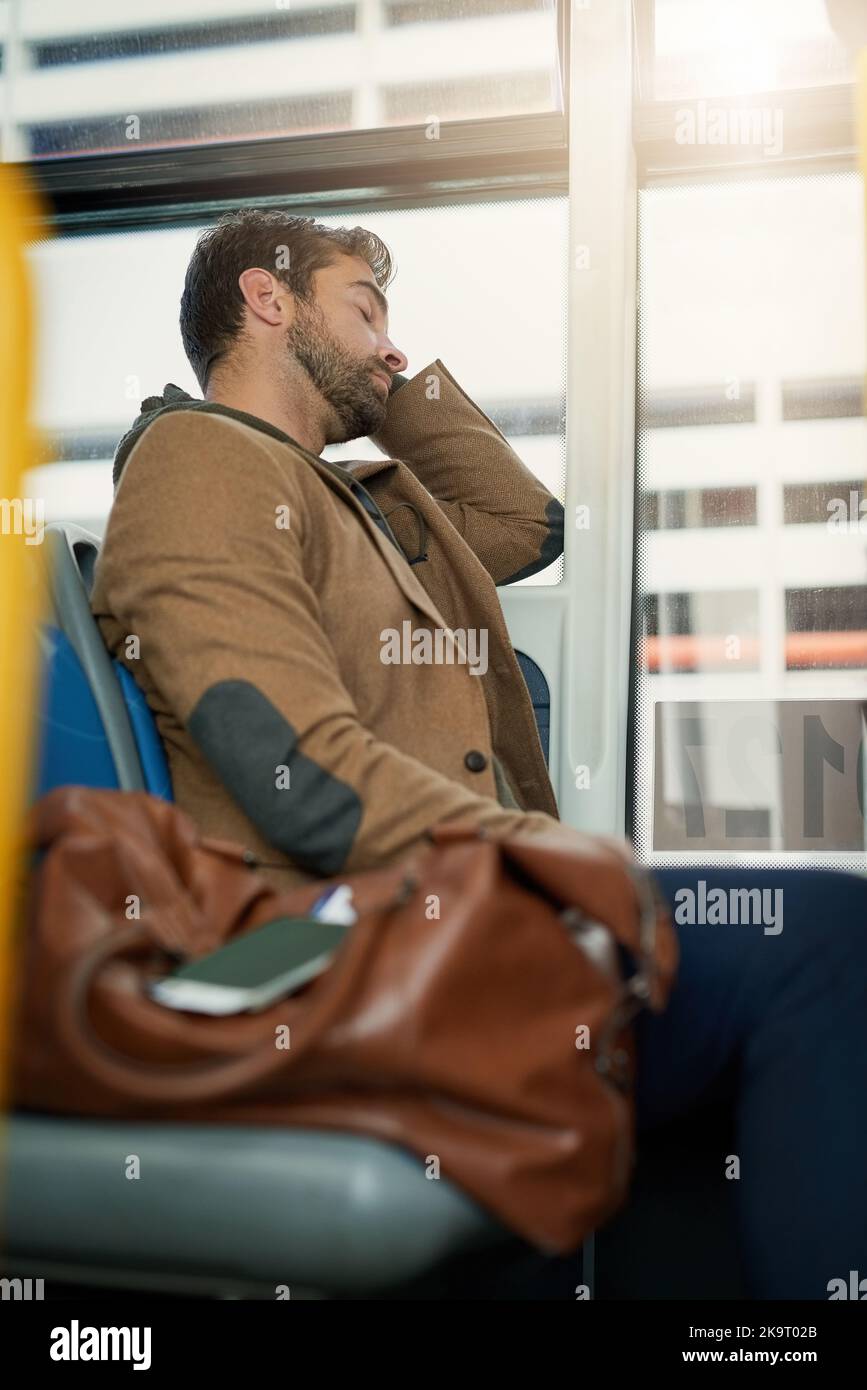 Ein hübscher junger Mann, der während seines morgendlichen Pendelvorgangs im Bus schläft. Stockfoto Ein hübscher junger Mann, der während seines morgendlichen Pendelvorgangs im Bus schläft. Stockfoto