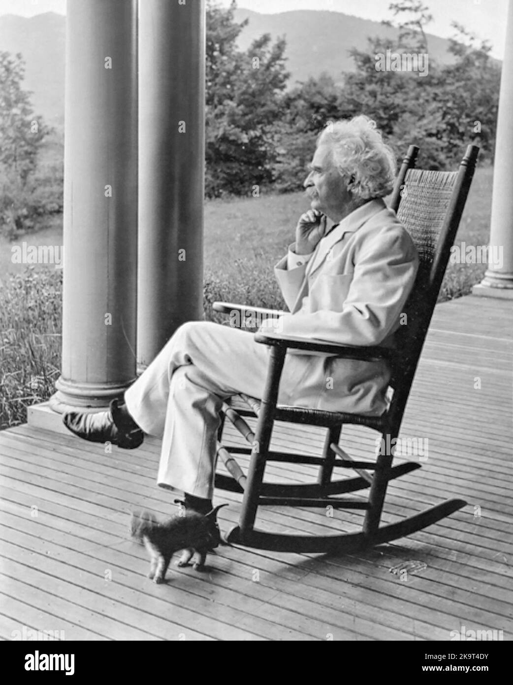 Der amerikanische Humorist und Schriftsteller Samuel Langhorne Clemens (bekannt unter seinem Pseudonym Mark Twain) sitzt 1906-1908 auf einer Veranda mit Schaukelstuhl in Dublin, New Hampshire. Stockfoto
