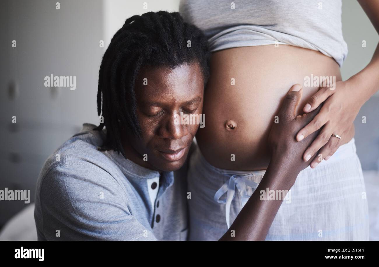 Ich verspreche, der beste Vater zu sein. Ein Mann, der seinen Ehefrauen den schwanger Bauch zuhört. Stockfoto