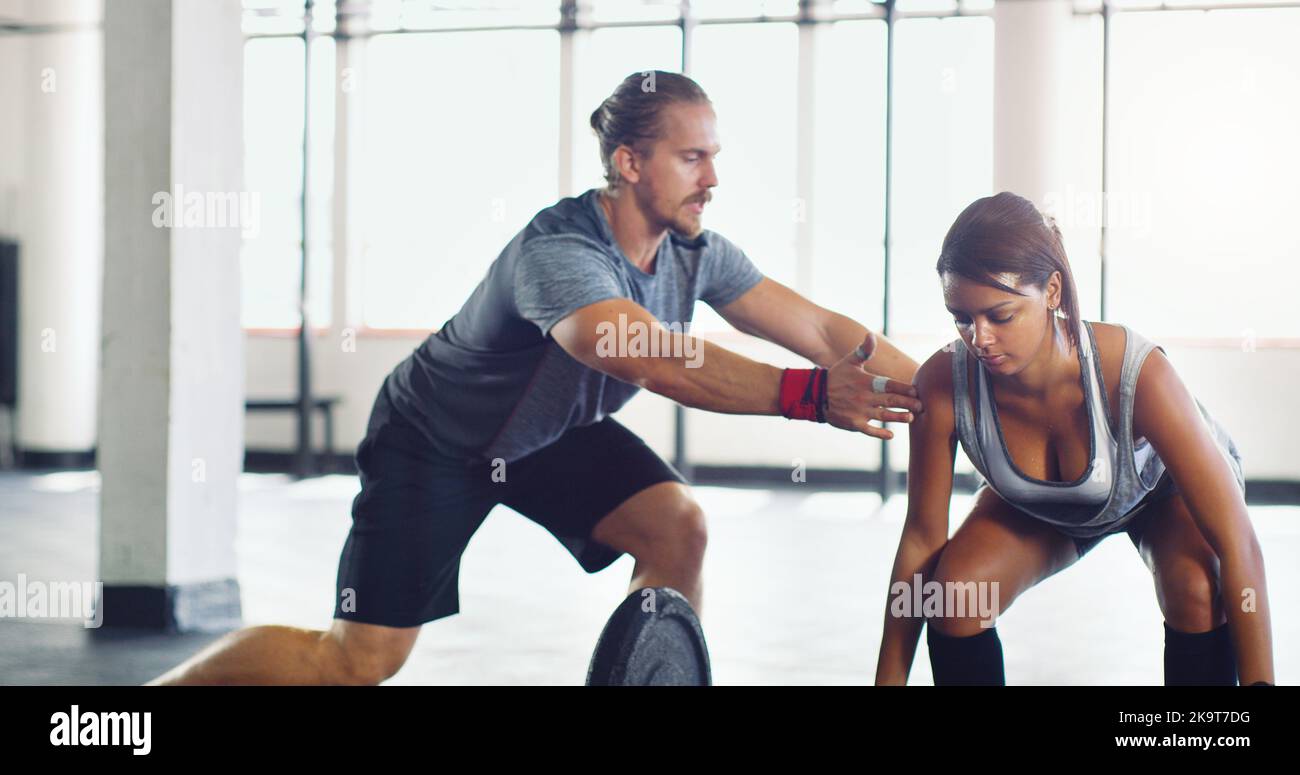 Lernen Sie vom Besten, um Ihr Bestes zu geben und zu fühlen. Eine junge Frau, die Gewichte hebt, unterstützt sie mit einem persönlichen Trainer in einem Fitnessstudio. Stockfoto