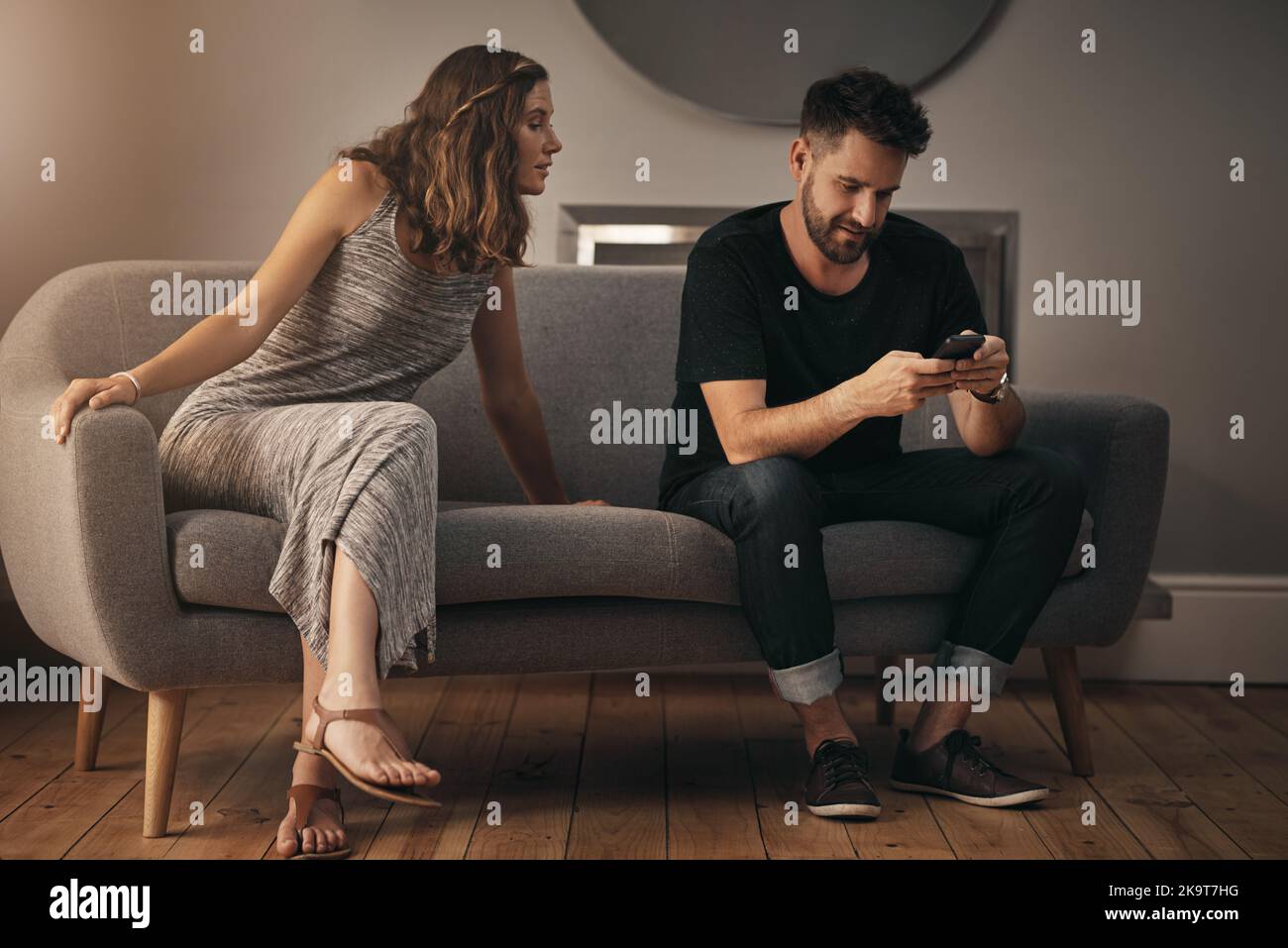 Ist das Vertrauen aus ihrer Ehe verschwunden. Eine junge Frau schaut sich an, was ihr Mann am Telefon tut. Stockfoto