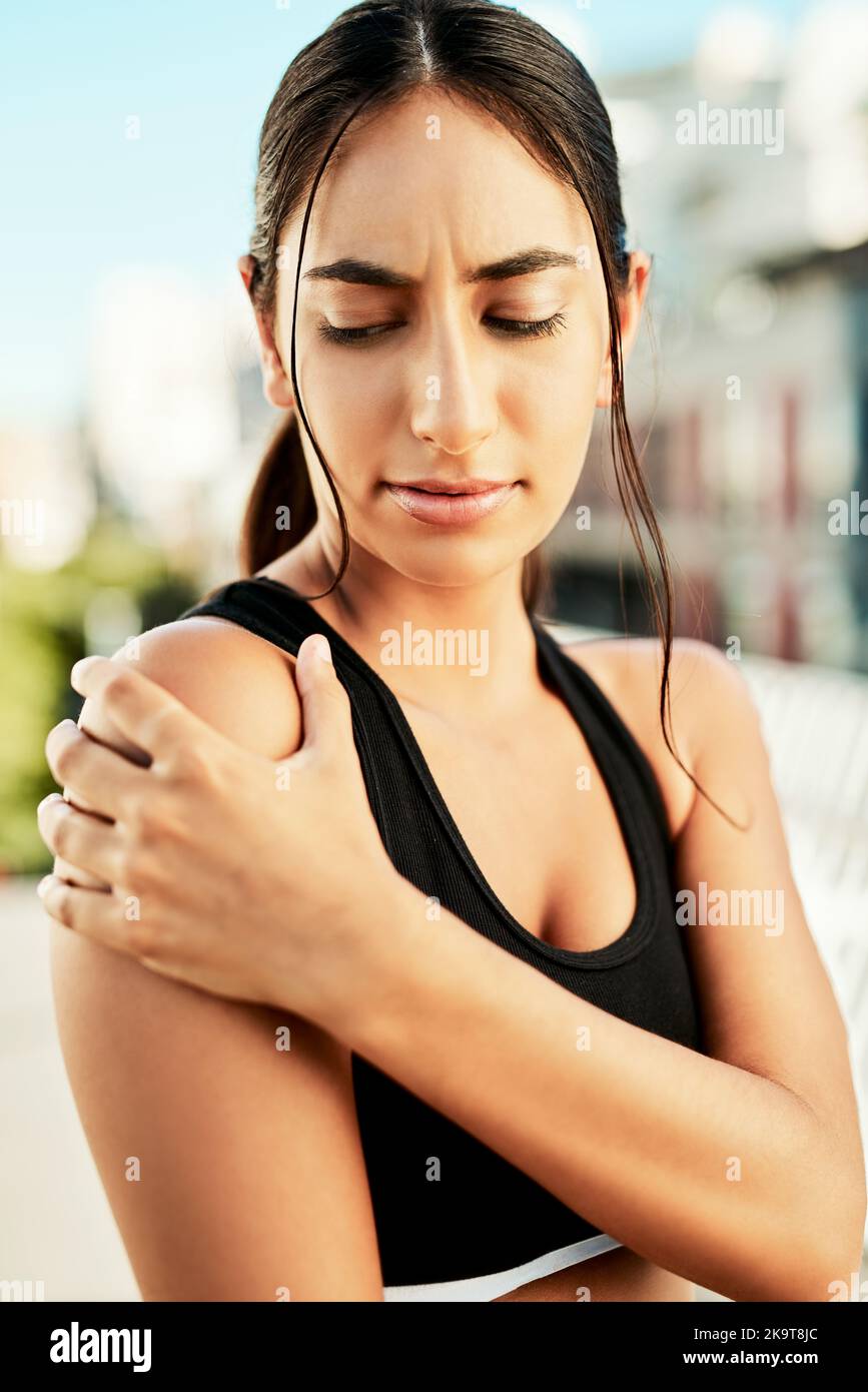Genau das, was ich befürchtet habe. Eine sportliche junge Frau, die ihre Schulter vor Schmerzen beim Training im Freien hält. Stockfoto