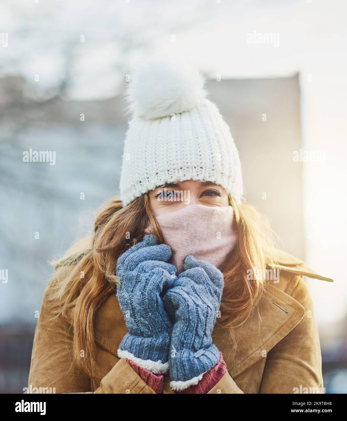 Es ist kalt, aber sehr gemütlich. Eine attraktive junge Frau genießt es, draußen im Schnee zu sein. Stockfoto