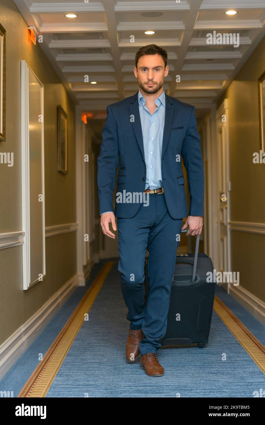 Glücklicher junger Mann mit Reisetasche, der ins Hotel ging Stockfoto