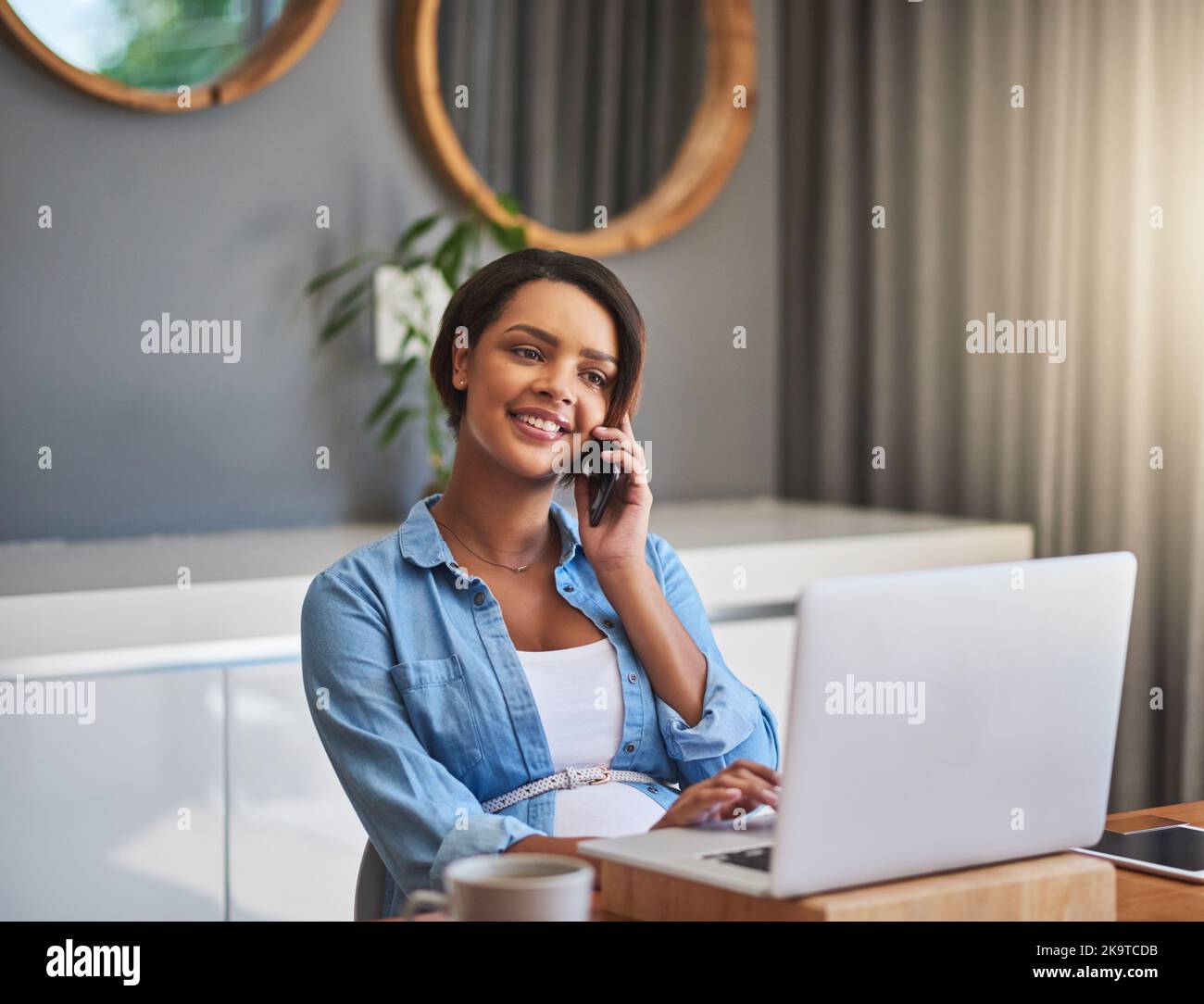Dinge geschehen zu lassen, bevor das Baby erscheint. Eine Schwangere junge Frau, die einen Laptop und ein Mobiltelefon benutzt, während sie von zu Hause aus arbeitet. Stockfoto