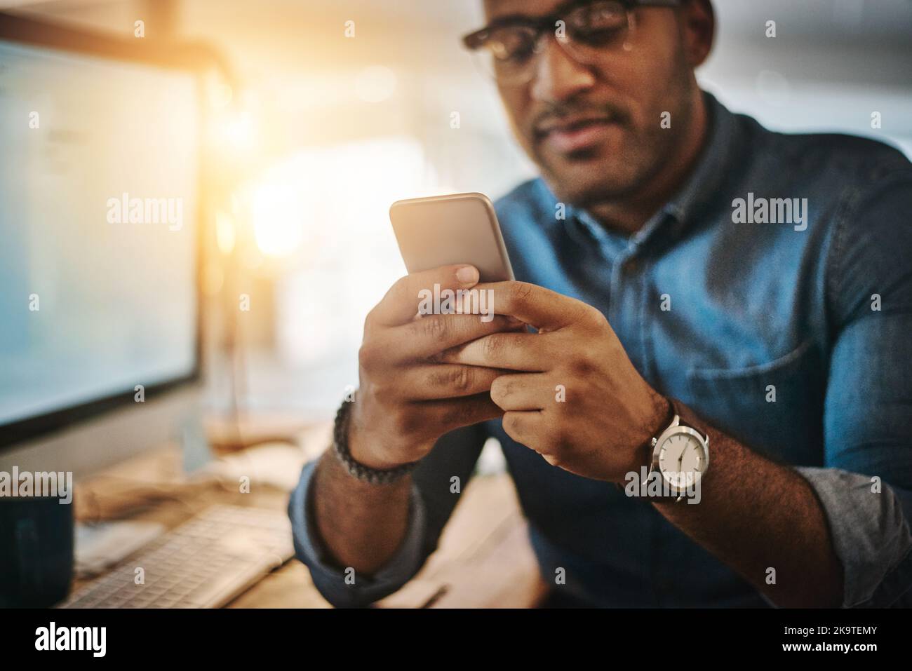 Die App, die es zu einer produktiven Nacht machte. Ein junger Geschäftsmann, der während einer späten Nacht auf der Arbeit ein Mobiltelefon verwendete. Stockfoto