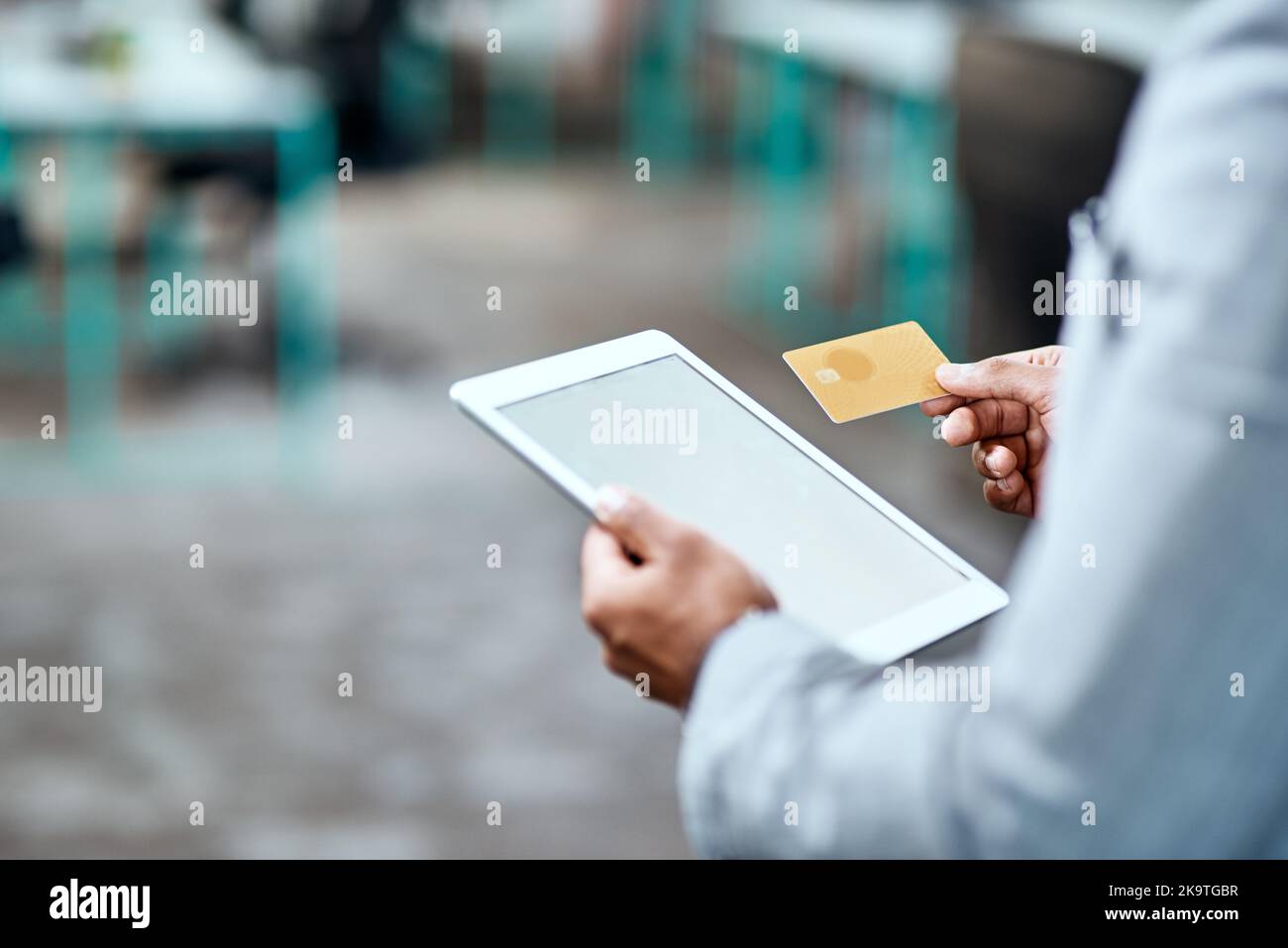 Begleichen Sie alle Ihre Geschäftskonten mit Leichtigkeit. Nahaufnahme eines nicht erkennbaren Geschäftsmannes, der in einem Büro eine Kreditkarte und ein digitales Tablet verwendet. Stockfoto