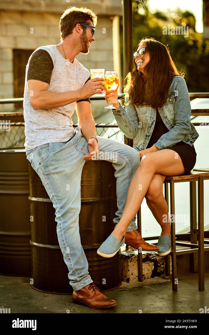 Die besten Momente im Leben werden mit Liebe gemacht. Ein attraktives junges Paar, das einen Drink hat und den Tag draußen auf dem Dach verbringt. Stockfoto