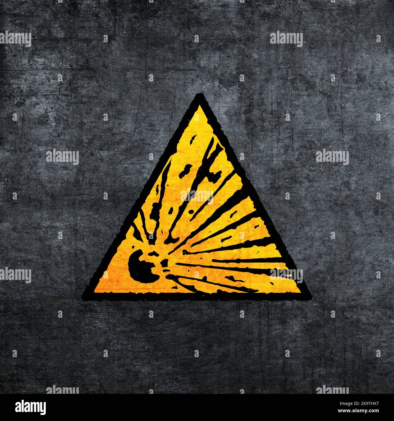 Explosives Warnschild, gelb auf grau. Symbol für Explosionsgefahr (Dreieck). Grunge-Textur-Effekt. Gelb auf Grau Stockfoto