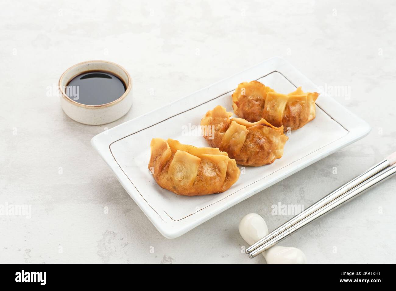 Gyoza, frittierte Knödel mit saftigem Huhn und Kohl. Serviert in weißem Teller mit Sojasauce Stockfoto