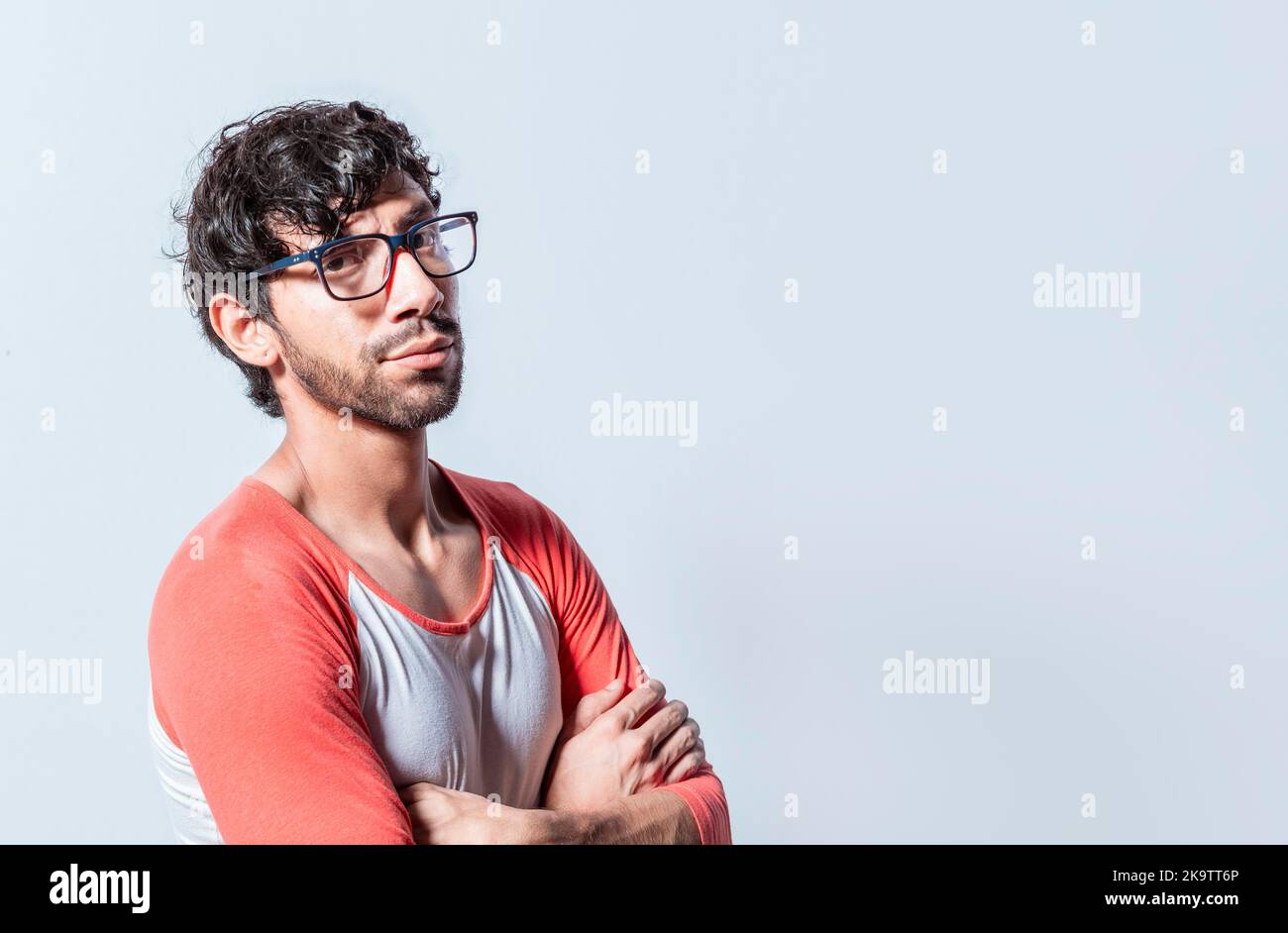 Porträt eines jungen Mannes mit verschränkten Armen isoliert. Junger latein in einer Brille mit gekreuzten Armen, der im Profil auf die Kamera blickt. Nicaraguanischer Mann mit Stockfoto