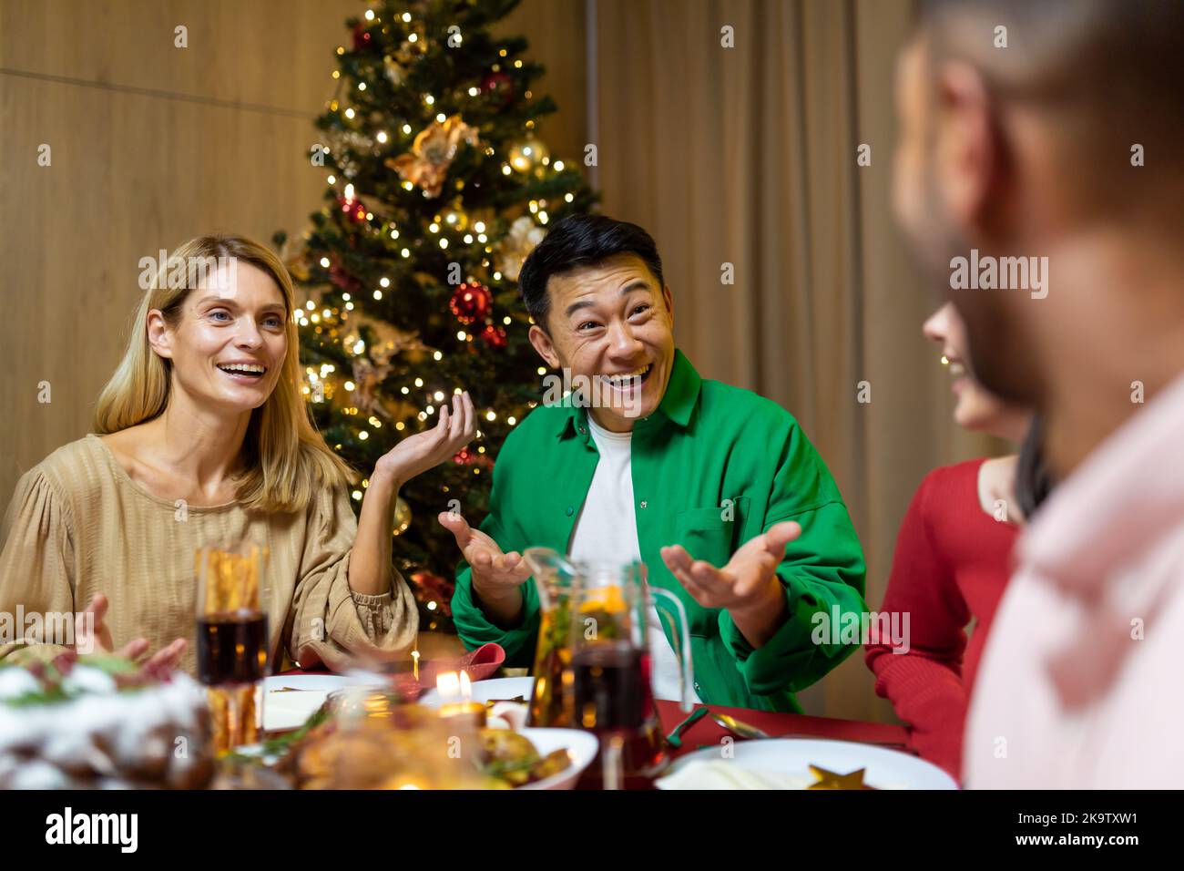 Freunde feiern Weihnachtsabend oder Silvester paty zusammen am Tisch sitzen. Schlemmen Sie zu Hause Gruppe von multi ethnischen festlichen weihnachtsessen. Glückliche fröhliche Menschen. Stockfoto