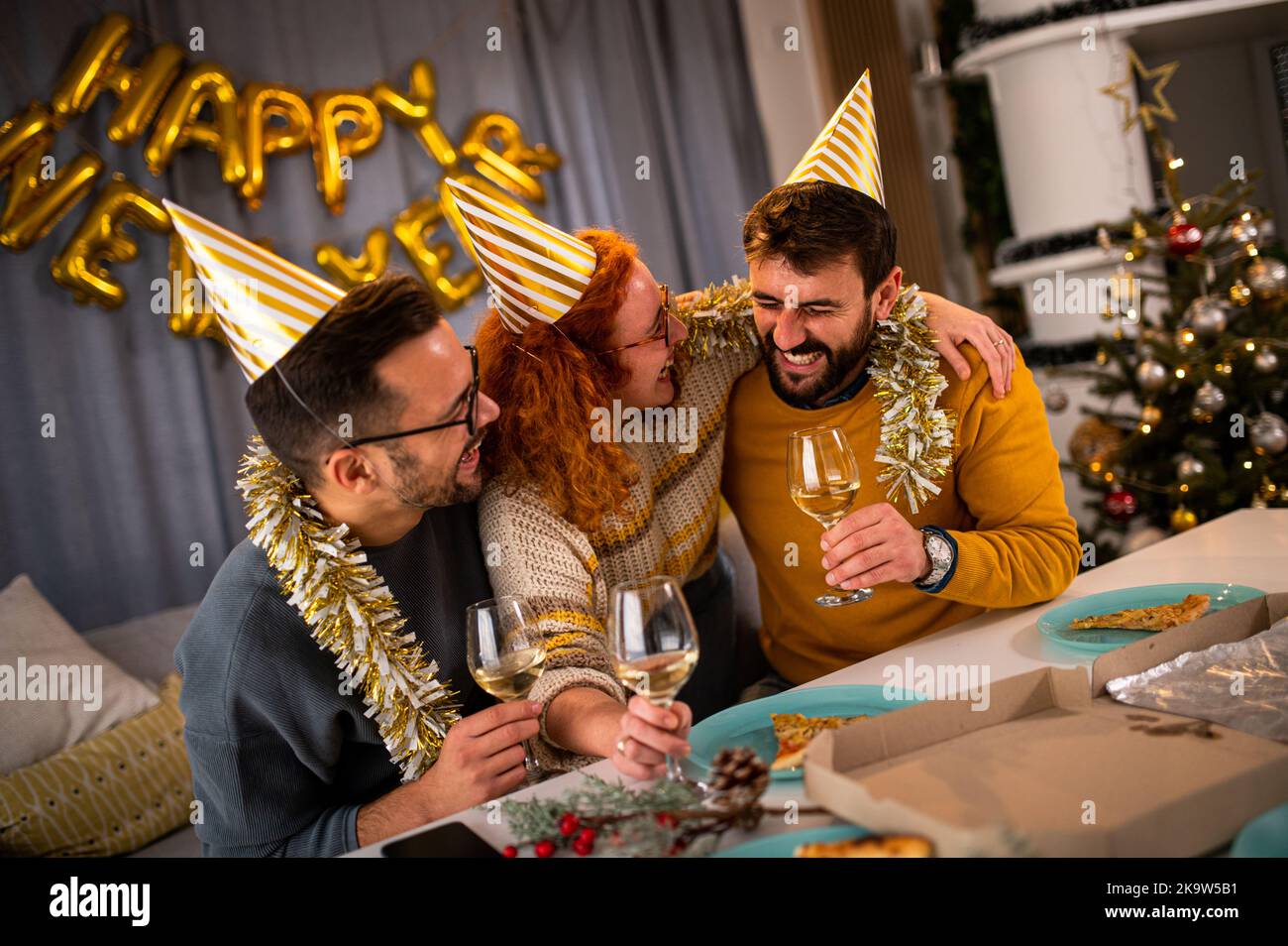 Junge Menschen, die lächelnd und lachend auf die Party zum neuen Jahr blicken und Wein und Champagner trinken. Stockfoto