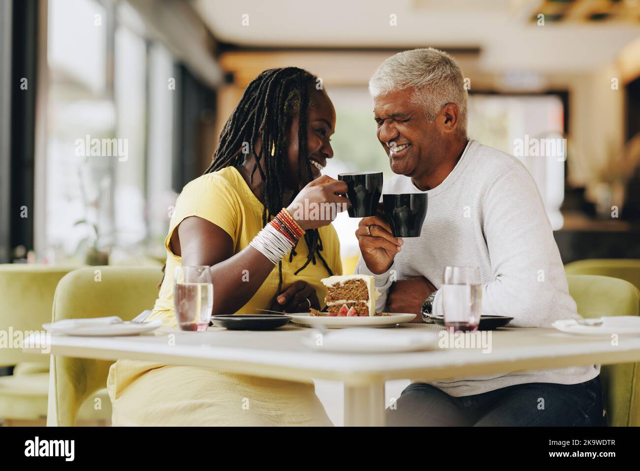Reifes Paar lacht fröhlich beim gemeinsamen Essen in einem Café. Sorgenfreies Seniorenpaar, das eine gute Zeit in einem Restaurant hat. Glücklicher, reifer Coup Stockfoto