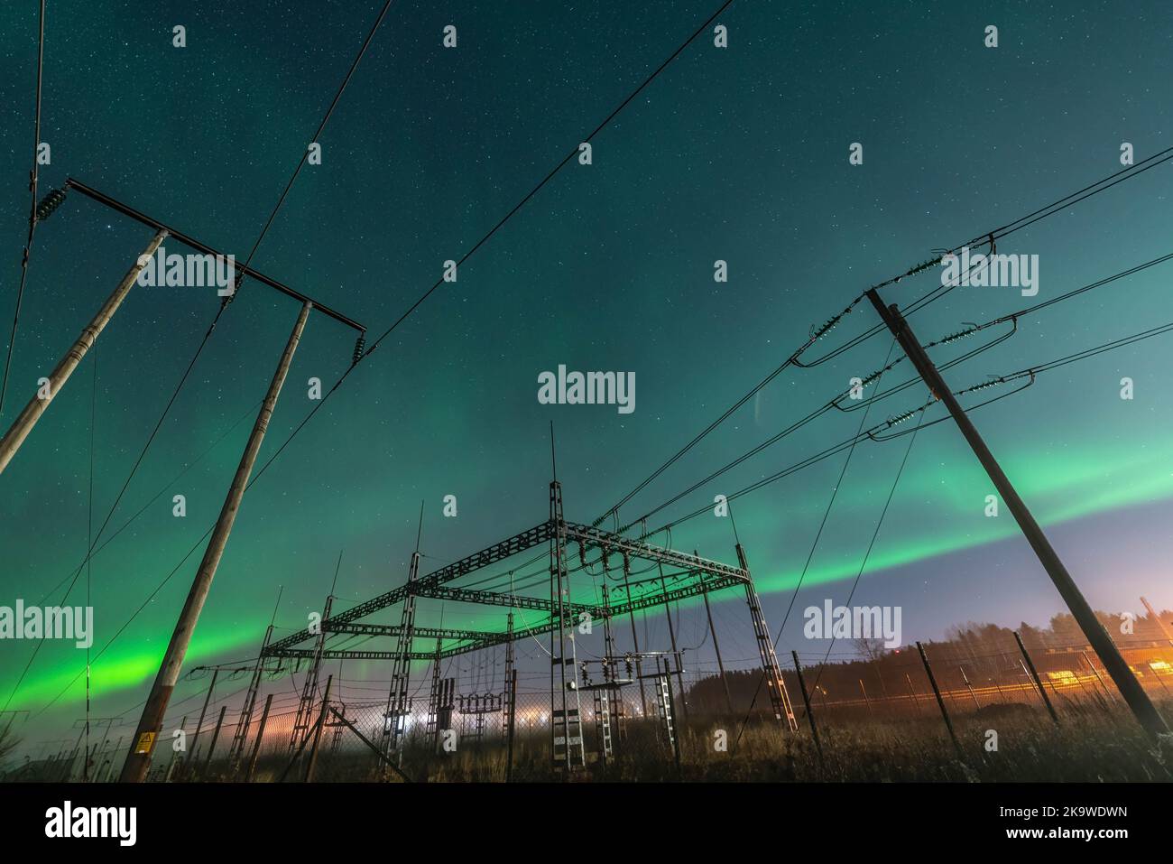 Wunderschöne Nachtlichter über elektrischen Umspannwerk und hölzernen Pol-Stromleitungen, Seitenansicht, Sternenhimmel mit Aurora Borealis. Schweden, Umea Stockfoto