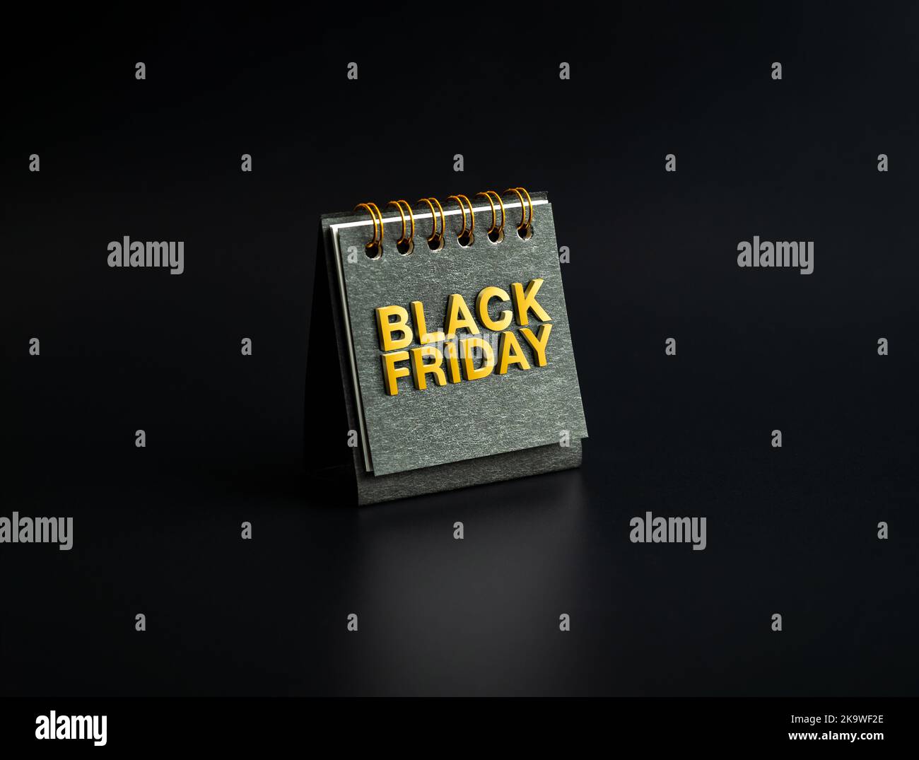Black Friday Verkaufskonzept. SCHWARZER FREITAG, goldenes Text-Flachrelief auf kleiner schwarzer Spiral-Tischkalenderhülle auf dunklem Hintergrund, minimalistisch. Inv Stockfoto