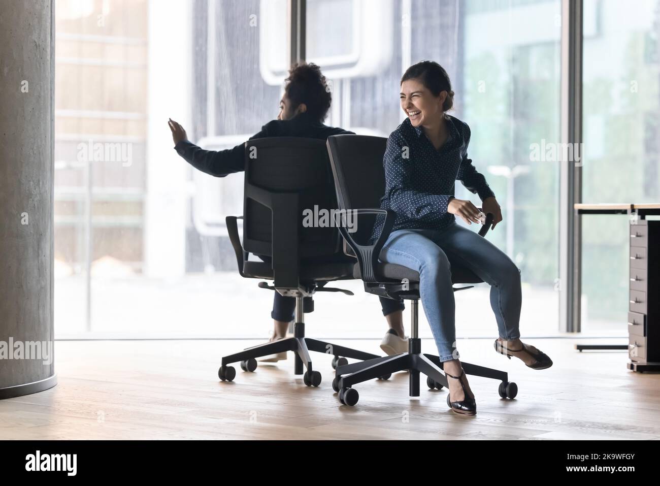 Fröhlicher indischer Büroangestellter, der auf Stühlen sitzt Stockfoto