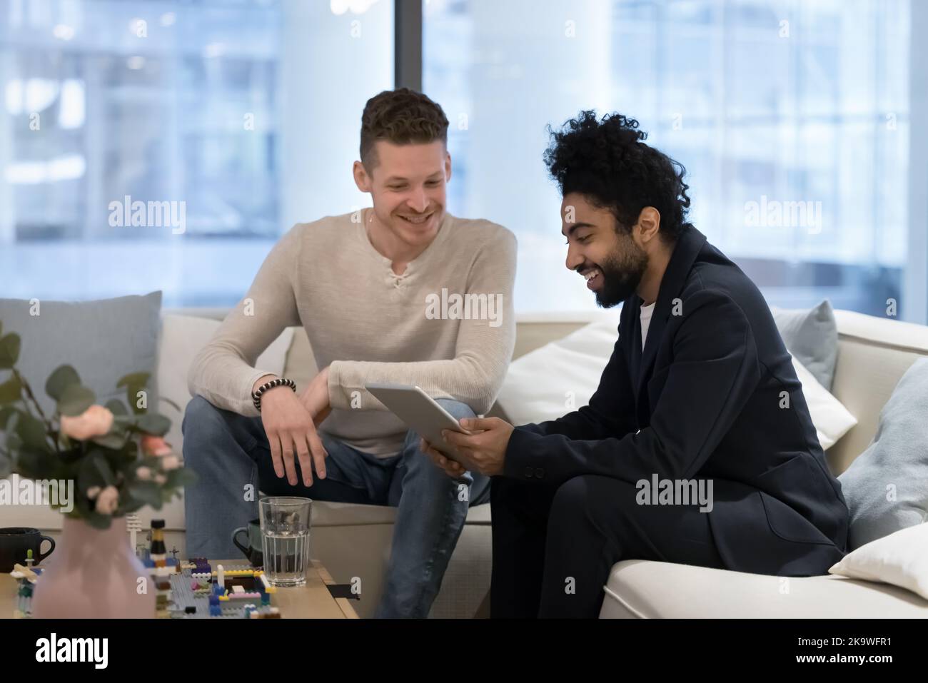 Zwei multiethnische Kollegen, Geschäftsleute, die im Büro ein digitales Tablet nutzen Stockfoto