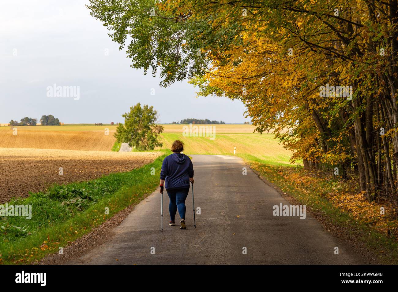 Plus size Frau, die auf der Straße läuft. Nordic Walking als gesunder Lebensstil und Gewichtsverlust Konzept. Stockfoto
