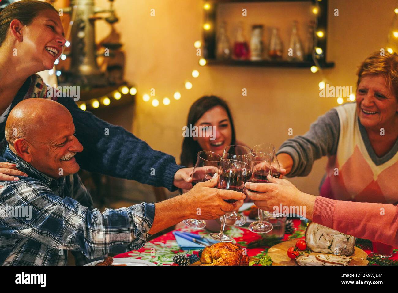 Fröhliche Familie jubelt mit Wein beim gemeinsamen Weihnachtsessen - konzentrieren Sie sich auf die linke Hand Stockfoto