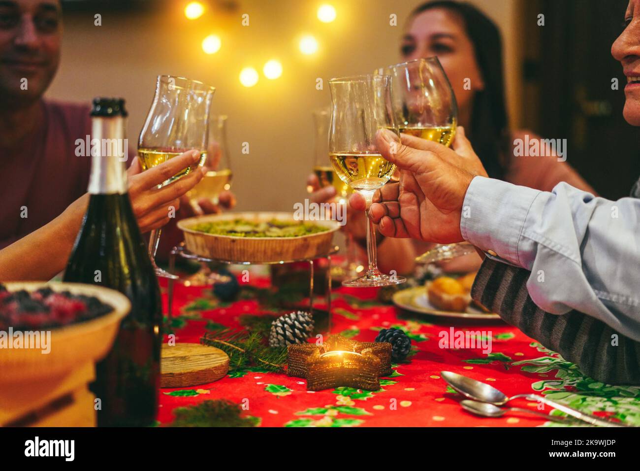 Fröhliche Familie jubelt mit Champagner beim gemeinsamen Weihnachtsessen - konzentrieren Sie sich auf das richtige Glas Stockfoto