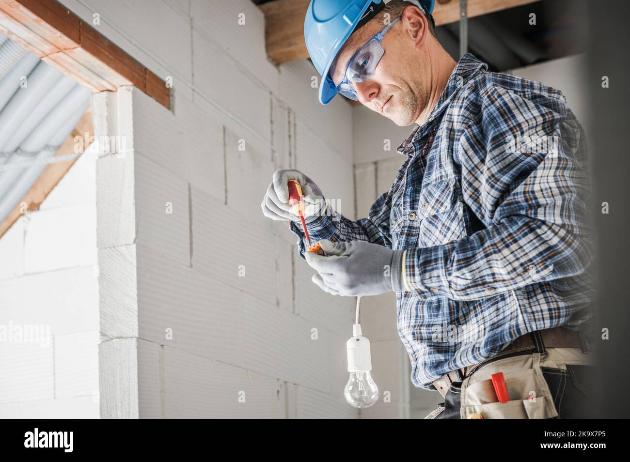 Professioneller Elektriker bereitet einen Lichtpunkt im neu erbauten Haus vor. Thema „Construction Zone“. Stockfoto