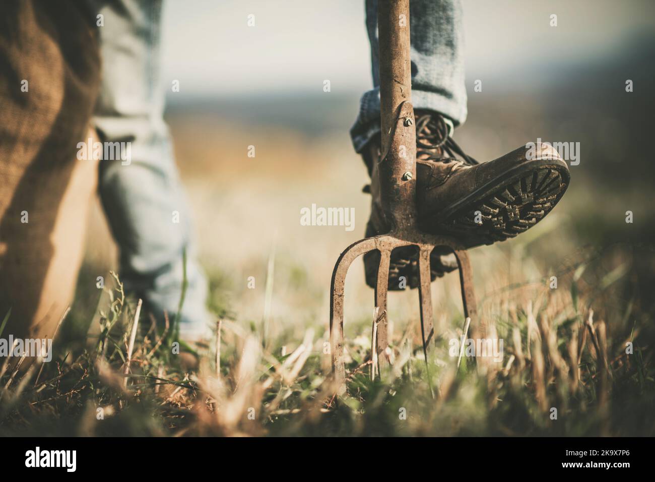 Cowboy Rancher, der sein Bein auf einer Gartengabel ausruht. Thema Landwirtschaft und Landwirtschaft. Stockfoto