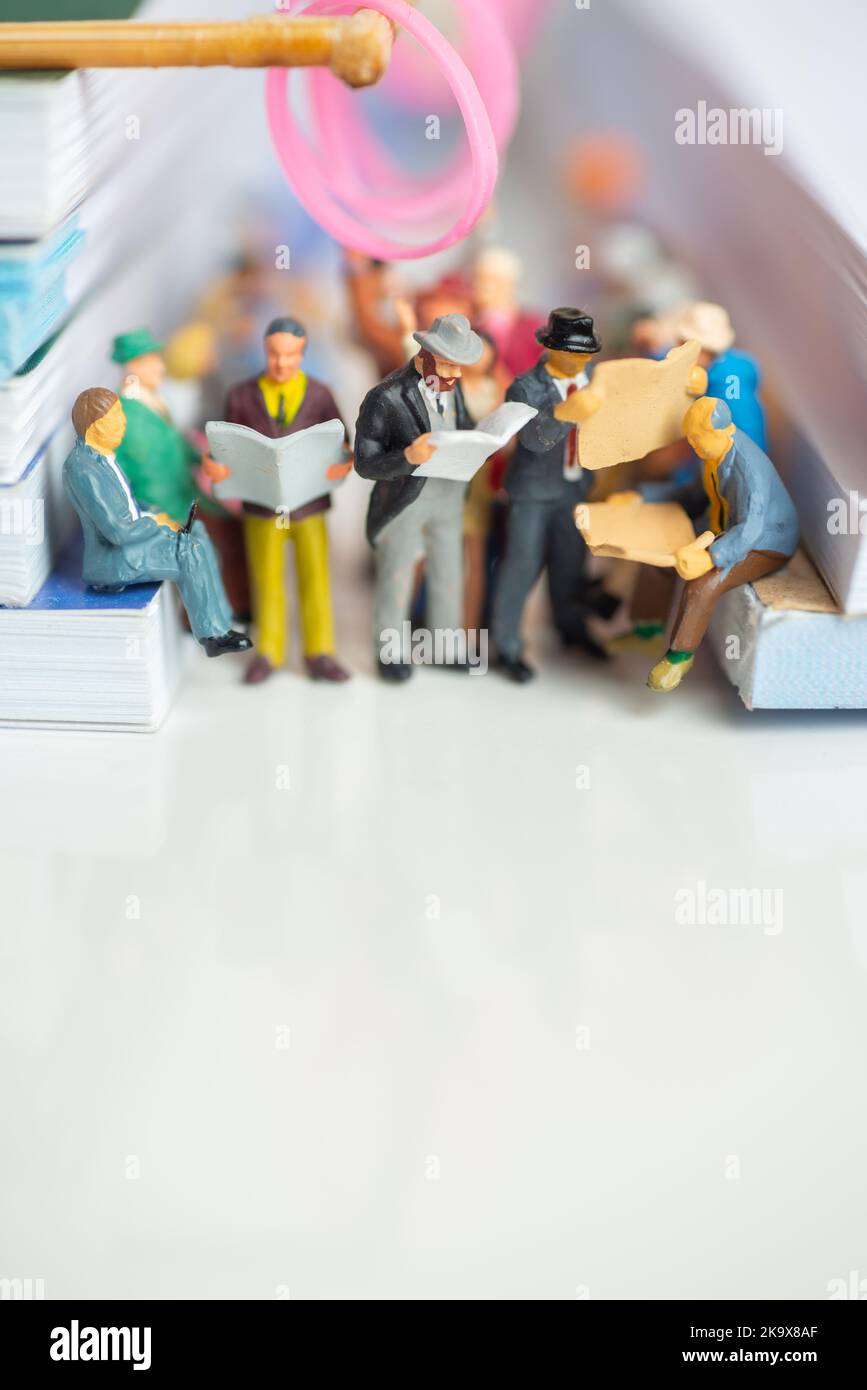 Miniaturspielzeug von Fahrgästen liest Zeitung und Menschen reisen von der Arbeit an einem öffentlichen Verkehrsmittel Konzept - Reisen in einem Zug oder Bus. Stockfoto