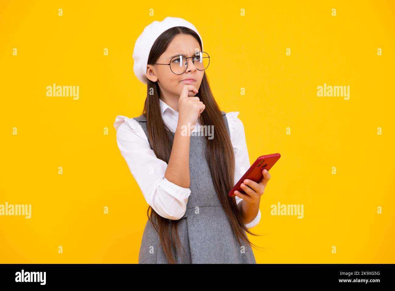 Teenager Kind mit Mobiltelefon. Nahaufnahme Porträt von niedlichen Teenager-Mädchen mit Handy, Zelle Web-App, isoliert auf gelbem Hintergrund. Denken Stockfoto