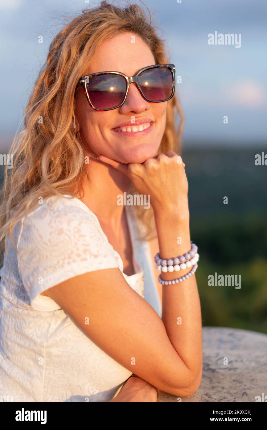 Junge positive sorglose kaukasische Frau in Sonnenbrillen, die den Sonnenuntergang im Freien genießen Stockfoto