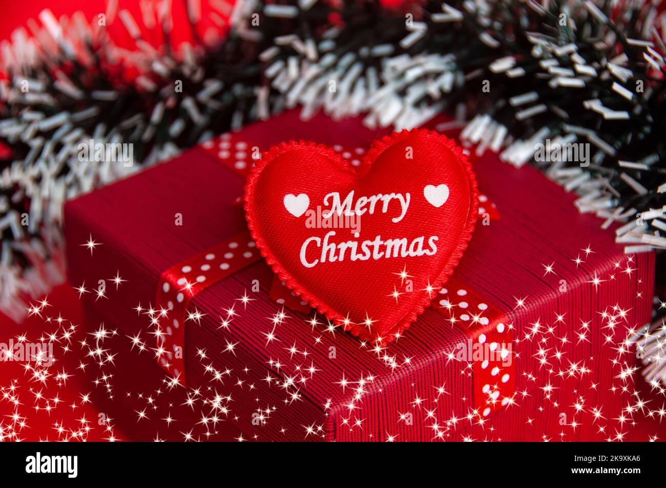 Frohe Weihnachten Text auf Herz-Form auf der Oberseite der roten Farbe Geschenk mit Weihnachtsdekoration Hintergrund. Stockfoto