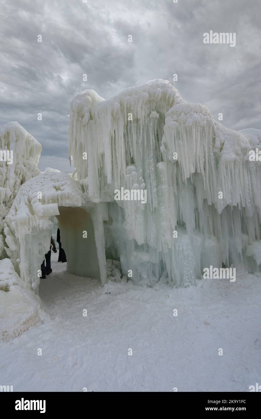 Eine aus Wasser und Eiszapfen entstandene Eiswand neben einem kleinen Tunnel aus Eis und Schnee auf der Ice Castle Show im Genfersee, Wisconsin, USA Stockfoto