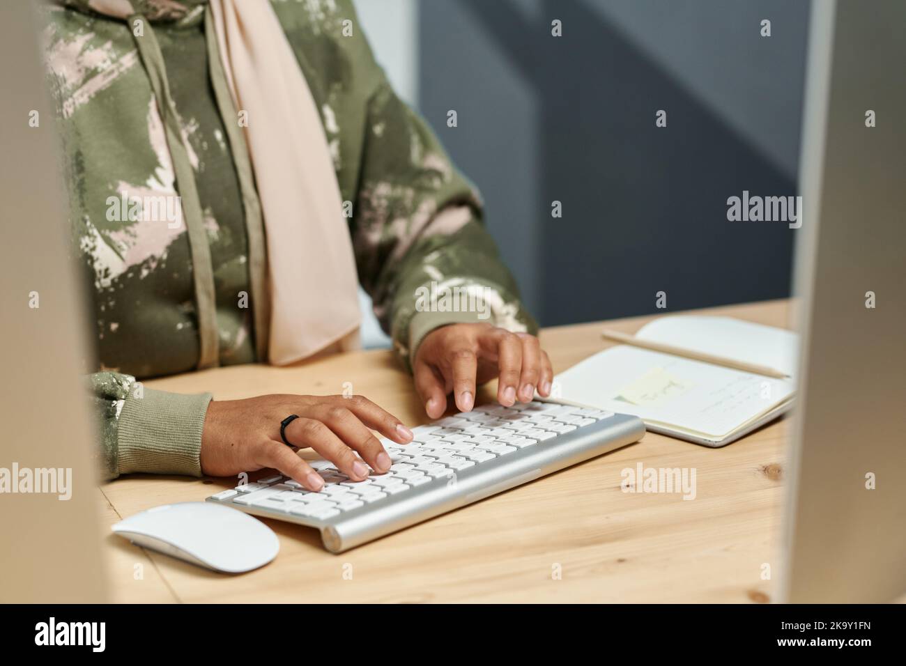 Hände einer jungen muslimischen Geschäftsfrau in der Freizeitkleidung, die auf der Computertastatur tippt, während sie neue Software entwickelt Stockfoto