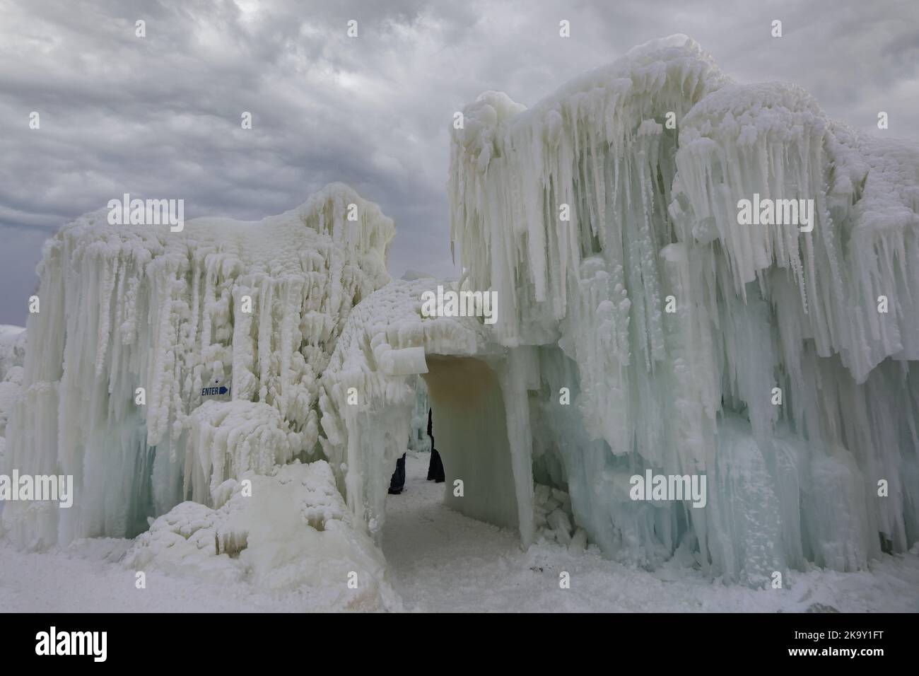Eine aus Wasser und Eiszapfen entstandene Eiswand neben einem kleinen Tunnel aus Eis und Schnee auf der Ice Castle Show im Genfersee, Wisconsin, USA Stockfoto