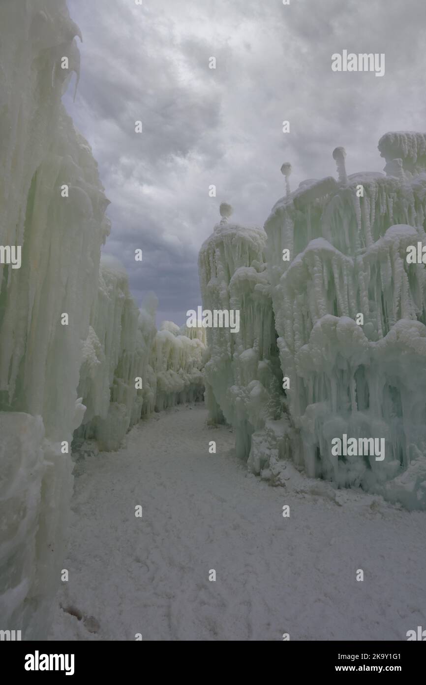 Ein Spaziergang auf einem Schneepfad neben einer Eiswand und einer großen Eisskulptur, die aus Wasser und Eiszapfen bei der Ice Castle Show im Genfer See, Wisconsin, geschaffen wurde, Stockfoto