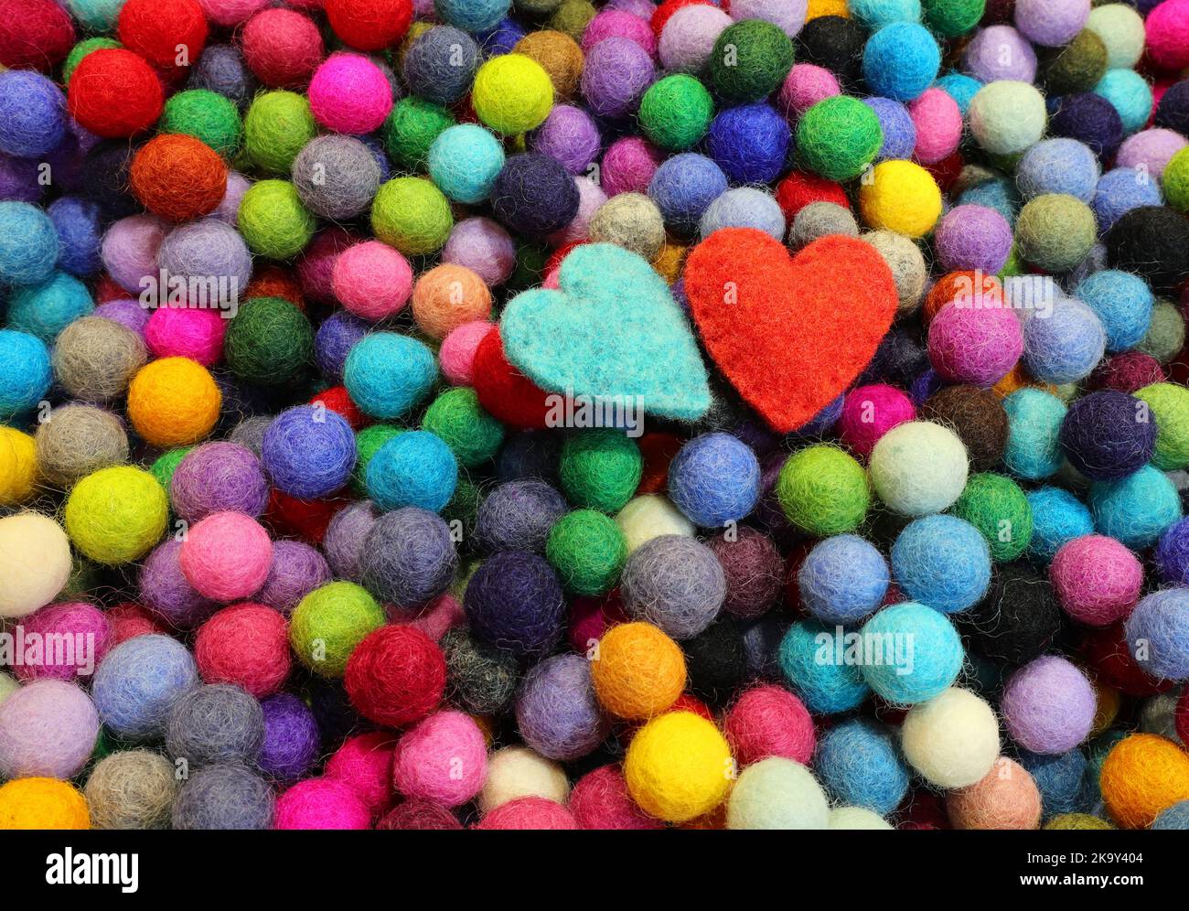 Kugeln aus geschnitzter Filzwolle und zwei blauen und roten Herzen Stockfoto