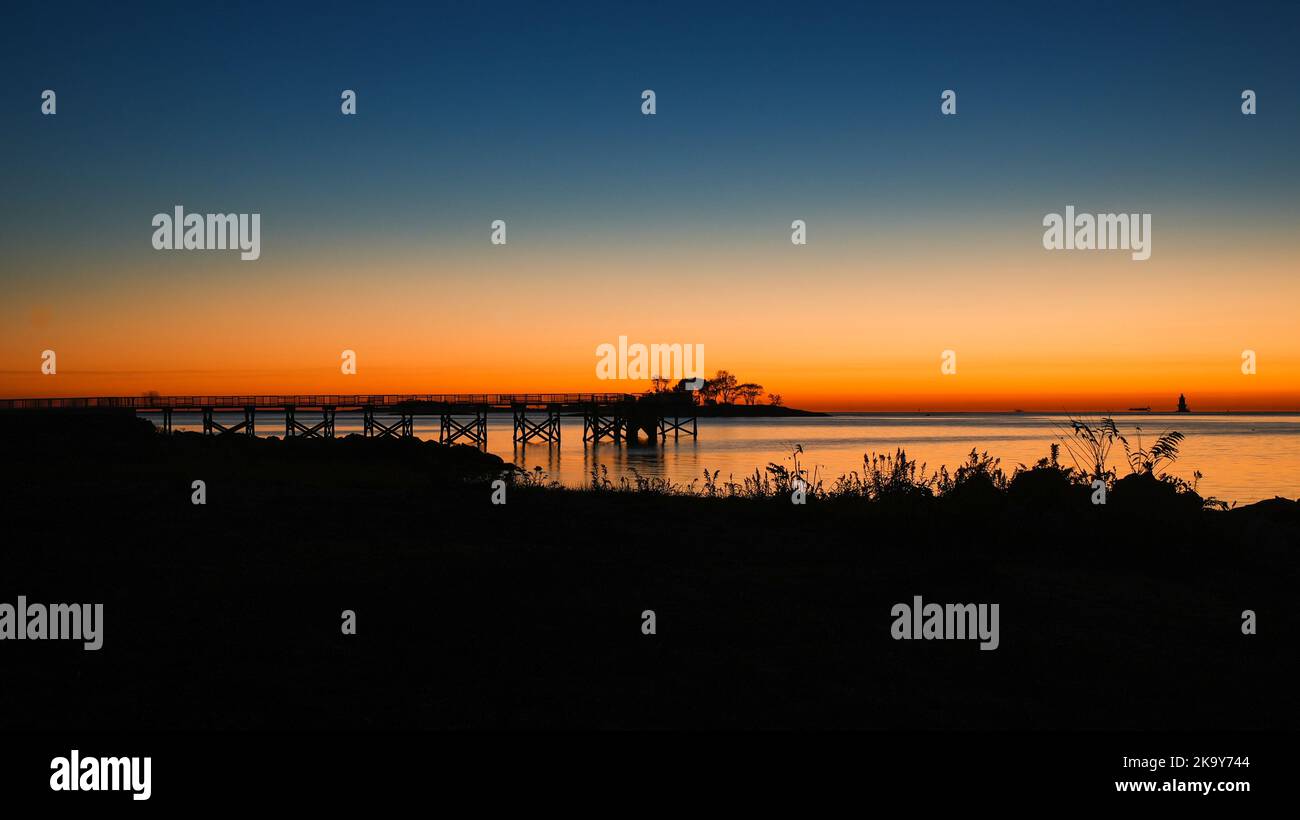 NORWALK, CT, USA - 30. OKTOBER 2022: Wunderschöner, farbenfroher Sonnenaufgang am Calf Weide Strand mit Fischerpier-Silhouette Stockfoto