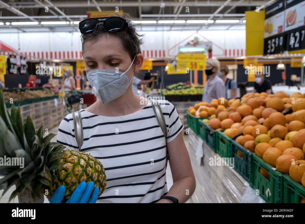 Asiatische Frau in Maske wählen Sie Obst Artikel in Supermärkten zu kaufen Stockfoto