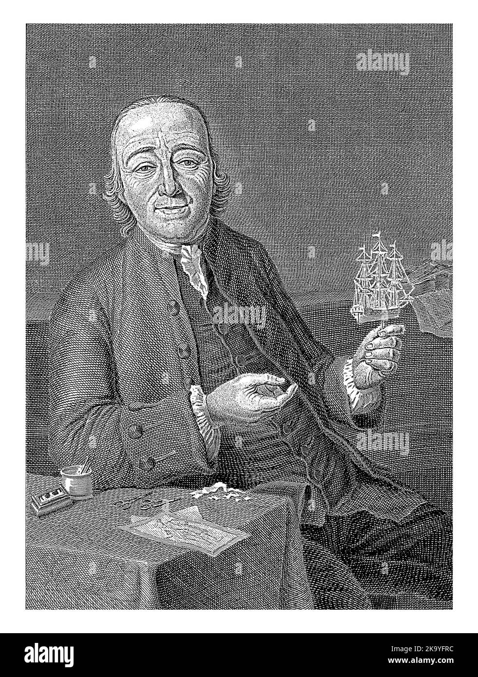 Porträt des Rotterdamer Papierkünstlers Jan Kopper. Er hält ein kleines Boot und auf dem Tisch vor ihm sind zwei Scheren und mehrere Stücke Stockfoto