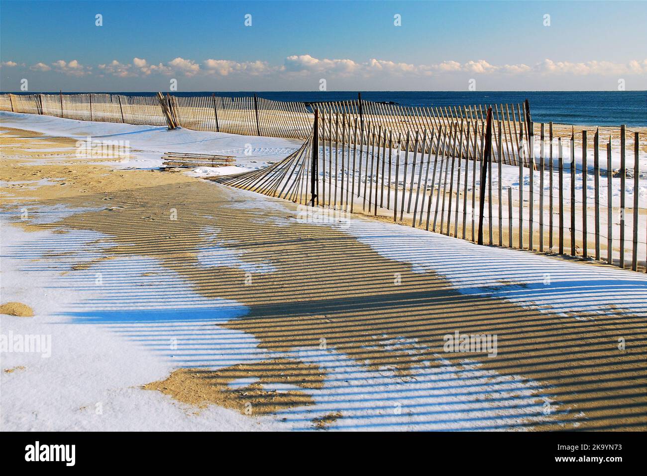Schnee bedeckt den Sand des Strandes während eines sonnigen Wintertages in der Nebensaison am Ufer Stockfoto
