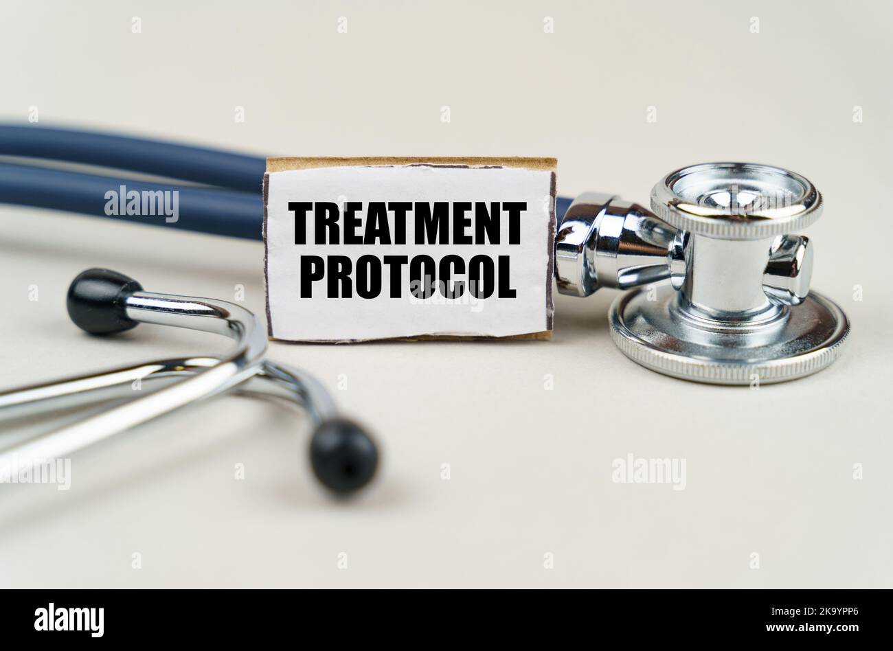 Medizinisches Konzept. Auf grauem Hintergrund ein Stethoskop und ein Pappschild mit der Aufschrift - Behandlungsprotokoll Stockfoto