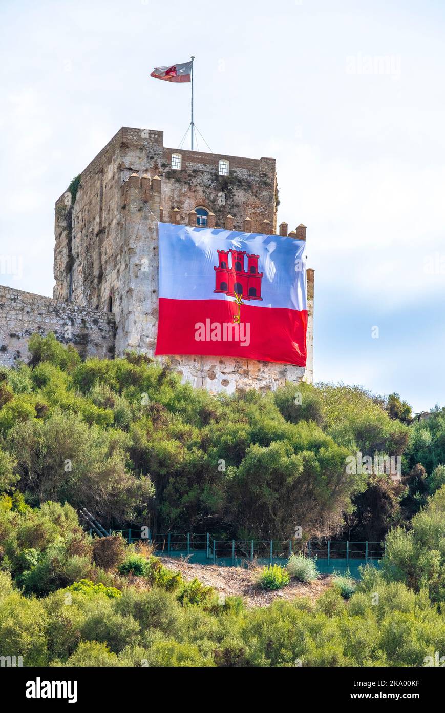 Blick auf die maurische Burg auf dem Upper Rock bei Gibraltar, mit der Flagge von Gibraltar an der Vorderseite des historischen Gebäudes. Stockfoto