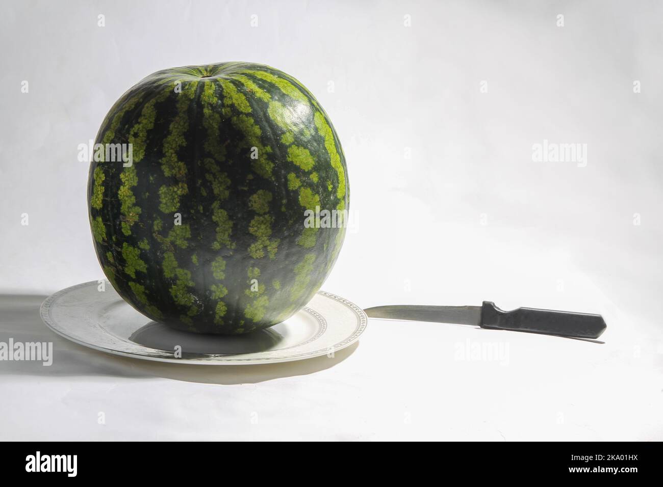 Wassermelone auf Whuit-Hintergrund und Messer - Herbstzeit - Erntezeit. Aus südlichen Regionen, die in die nördlichen Länder liefern (aus Spanien und zypern Stockfoto