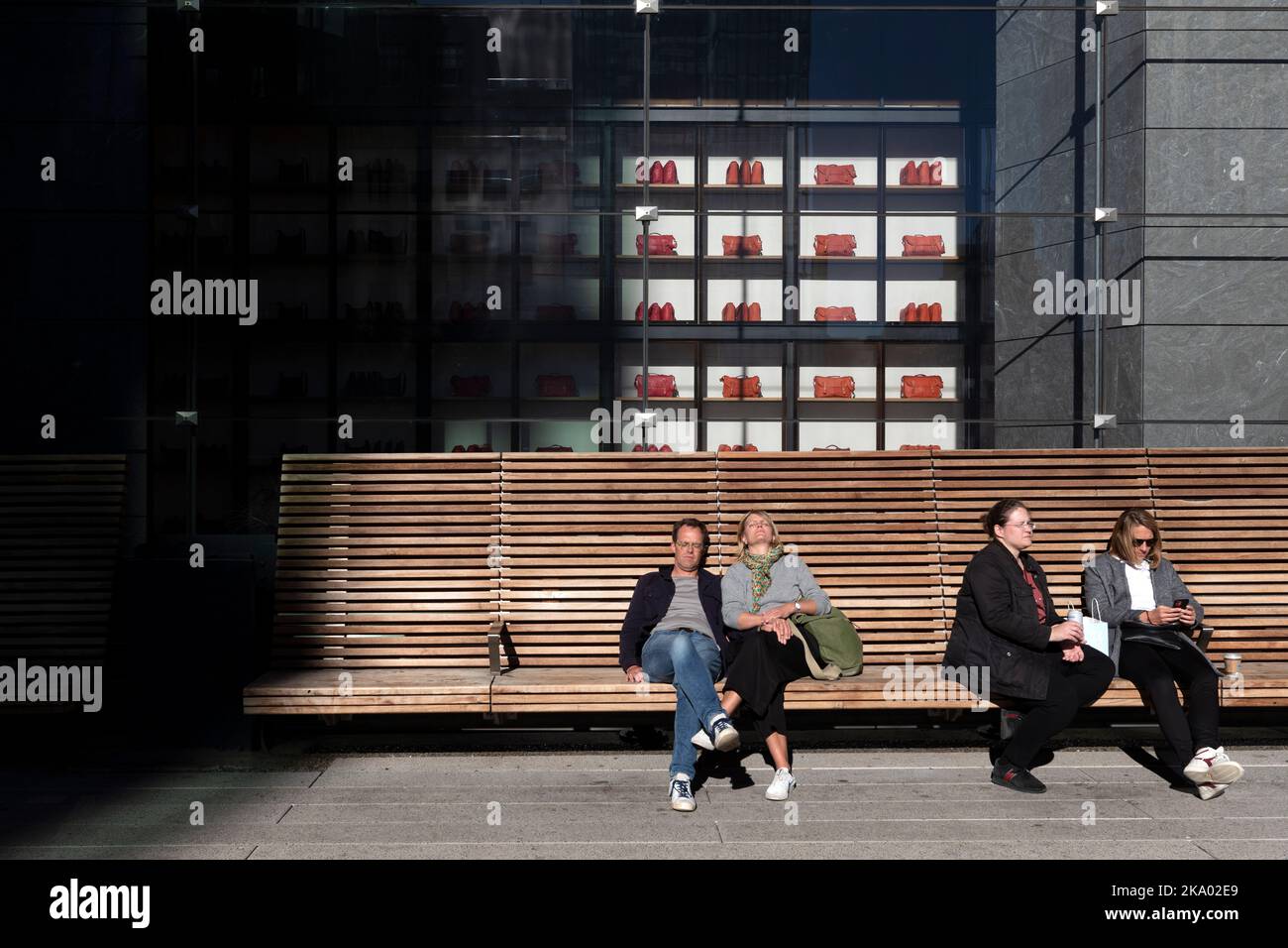 Menschen, die auf einer Bank an der High Line vor dem Coach Store in Hudson Yards, Chelsea, Manhattan, New York sitzen Stockfoto