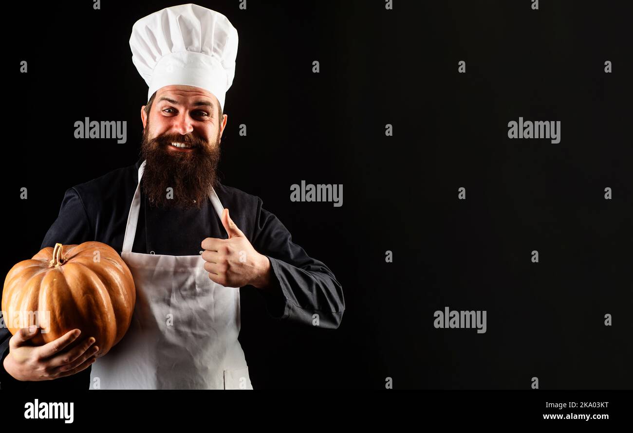 Mann in Chefuniform mit Kürbis, der den Daumen nach oben zeigt. Nützliches Gemüse. Herbsternte. Kochrezept. Stockfoto