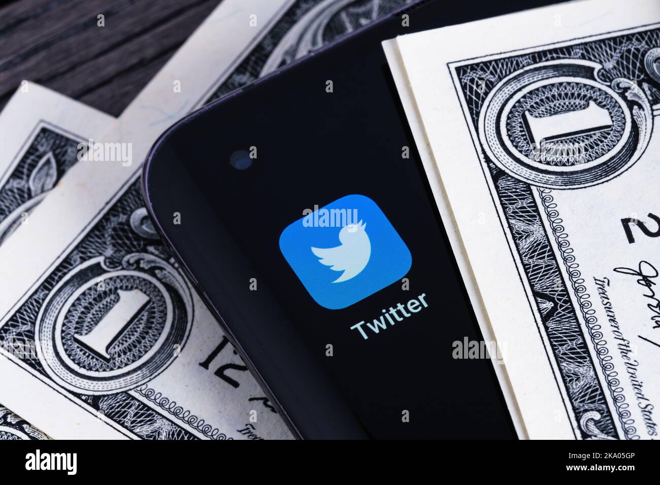 Twitter-App auf dem Bildschirm des Smartphones zwischen US-Dollar-Banknoten platziert gesehen. Konzept. Stafford, Großbritannien, 30. Oktober 2022 Stockfoto