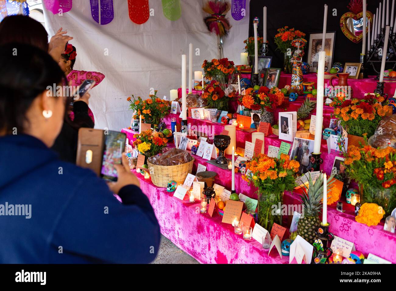 New York, NY, USA. 30. Oktober 2022. Mano a Mano: Die mexikanische Kultur ohne Grenzen (Cultura Mexicana Sin Fronteras) veranstaltete in der Markuskirche in der Bowery eine Feier des Dia de Muertos mit einem Gedenkaltar mit Opfergaben, Fotografien und schriftlichen Erinnerungen sowie mexikanischem Essen, Kunsthandwerk und Unterhaltung. Eine Frau fotografiert den Altar. Quelle: Ed Lefkowicz/Alamy Live News Stockfoto