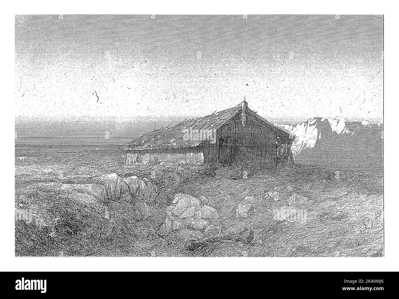 Auf einer Ebene mit Felsbrocken steht eine große Hütte. Berge sind im Hintergrund. Stockfoto