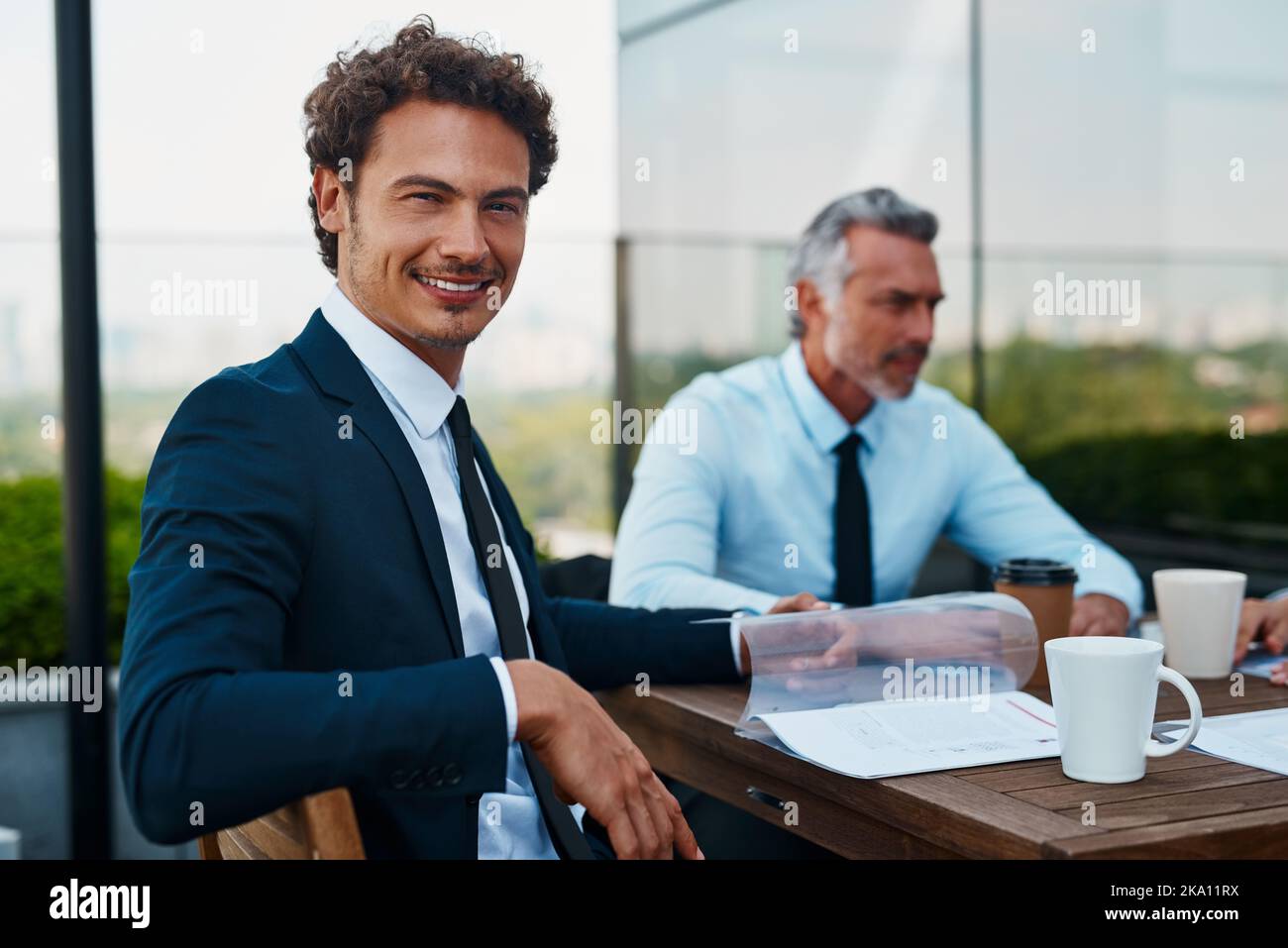 Besprechung von Unternehmensangelegenheiten mit etwas Kaffee. Geschäftsmänner, die sich draußen treffen. Stockfoto