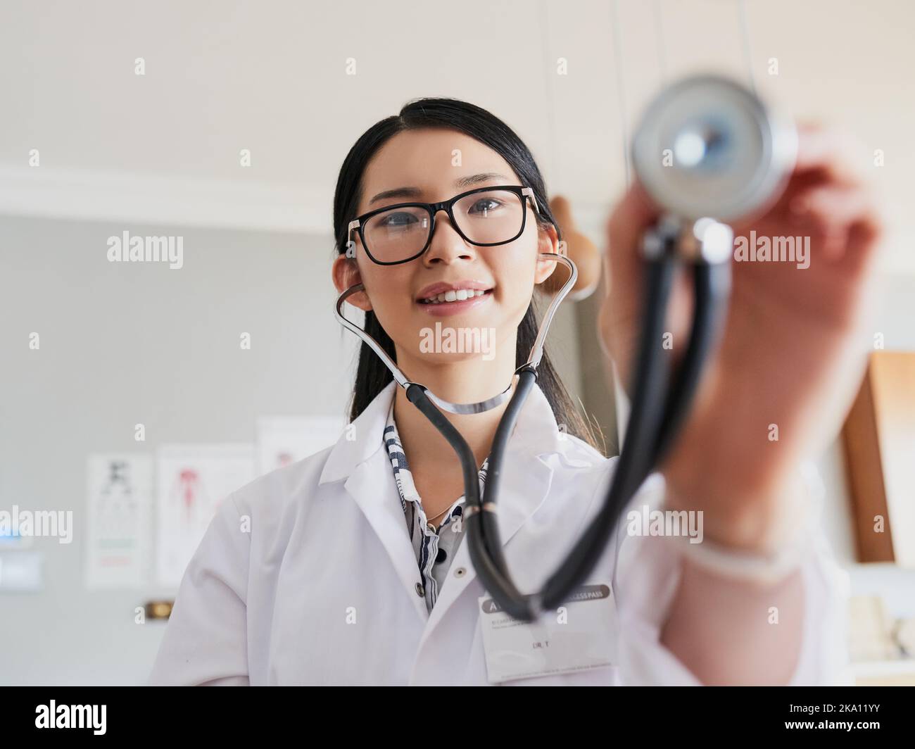 Eine junge Ärztin, die sich mit einem Stethoskop ausstreut, um Ihrem Herzschlag zuzuhören. Stockfoto